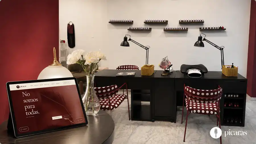 Interior del centro Pícaras con una tableta mostrando su web, flores y puestos de manicura.